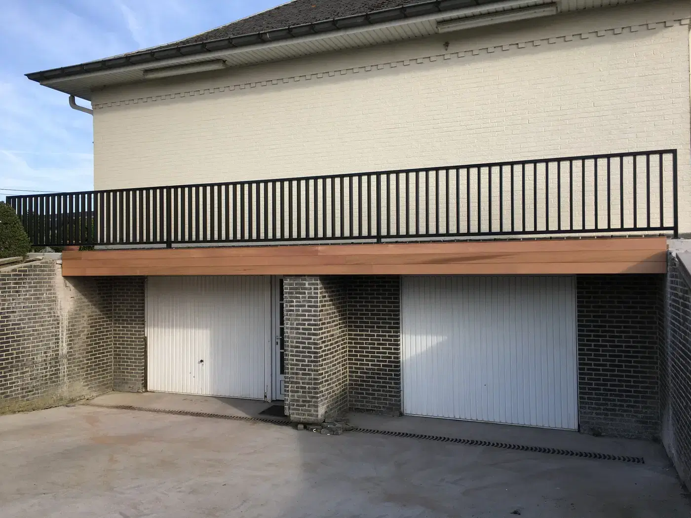 Gerenoveerd balkon met strakke zwarte balustrade op een houten rand