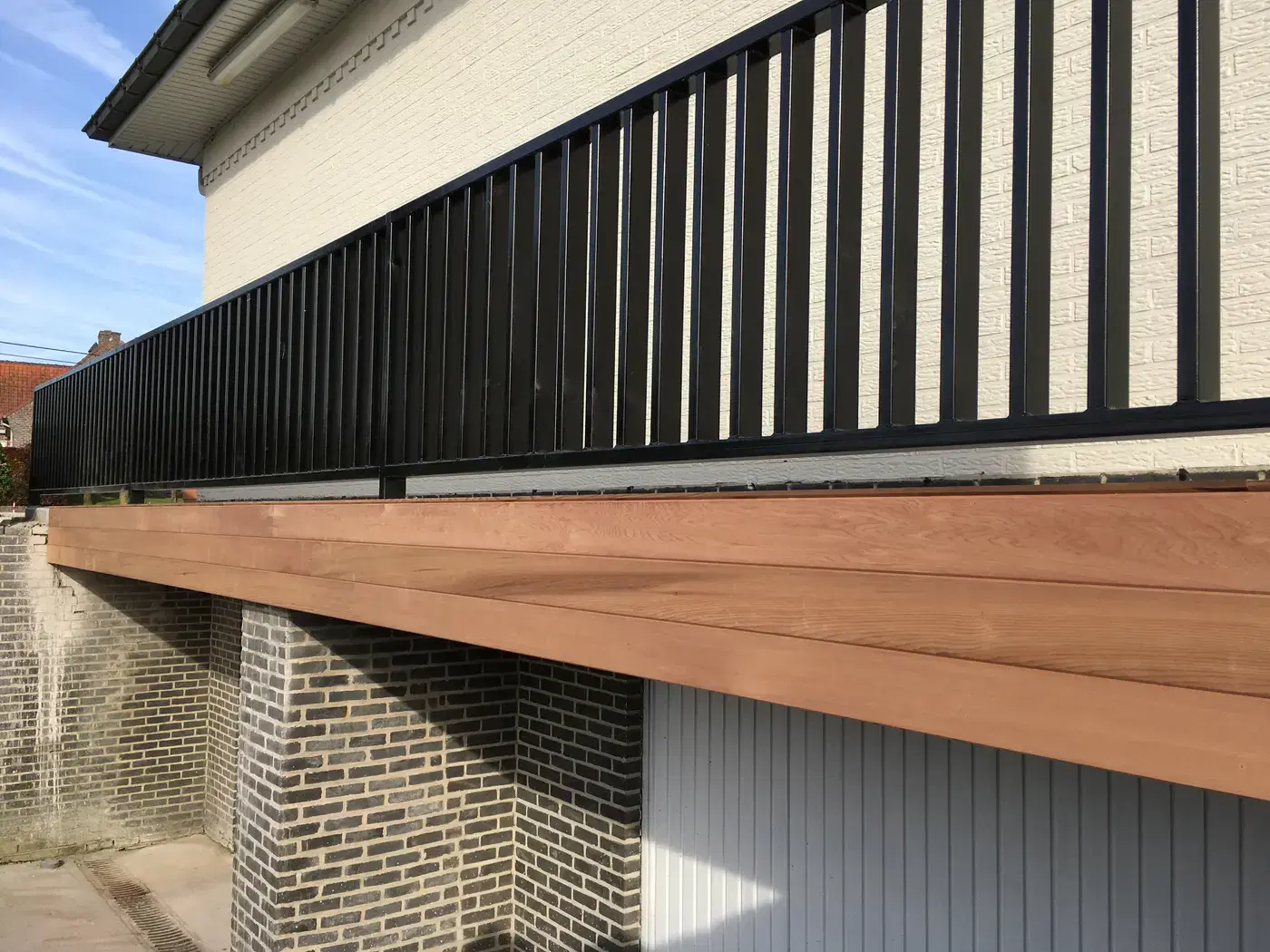 Zwarte spijlenbalustrade en houten balkonrand in diagonaal perspectief
