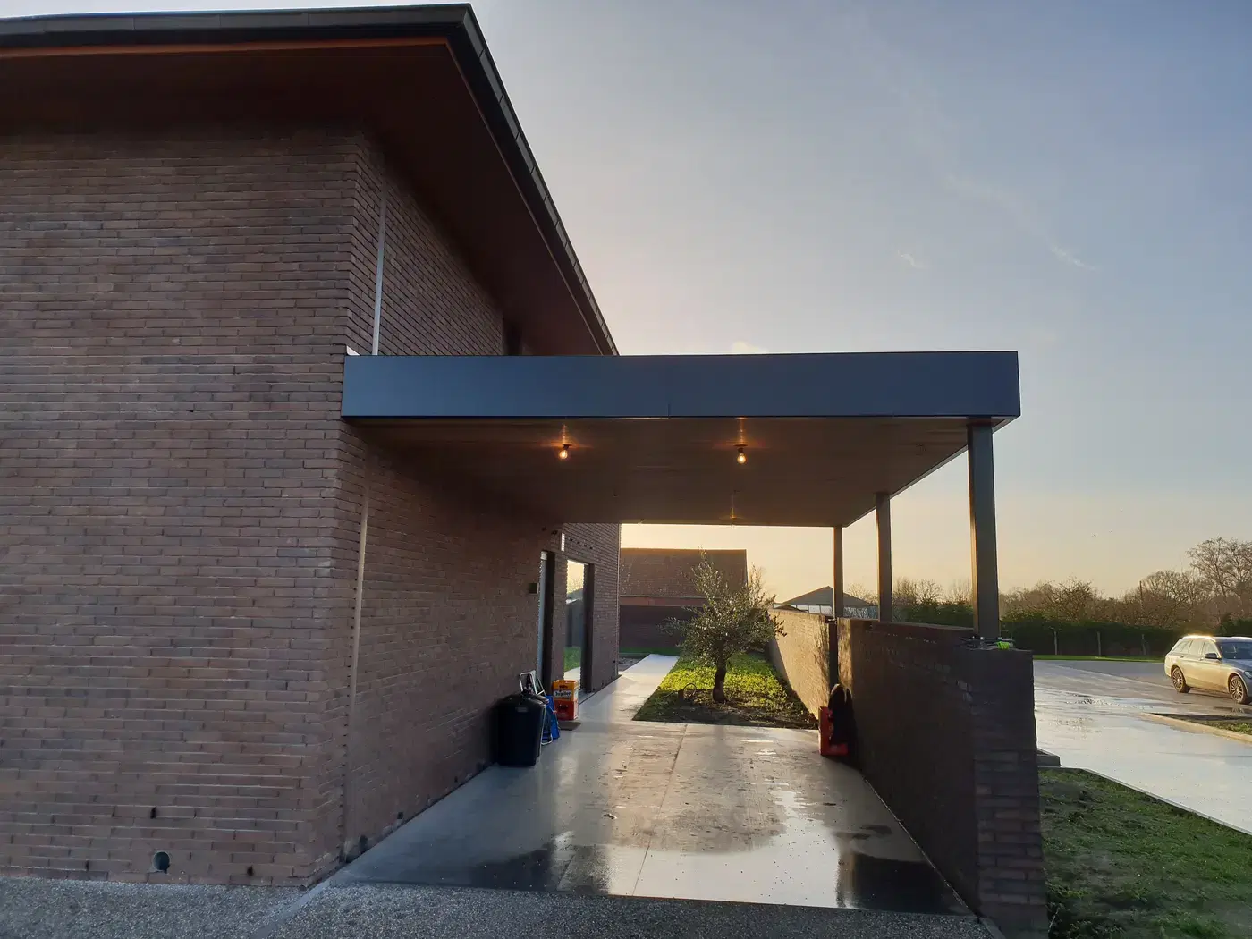Doorkijk onder de carport bij zonsondergang met verlichting aan