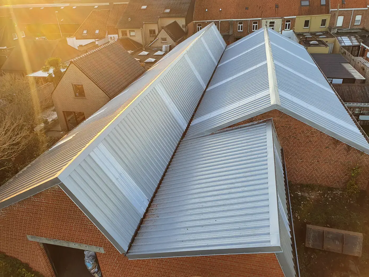 Vernieuwde metalen daken in warm avondlicht, gezien vanuit de lucht