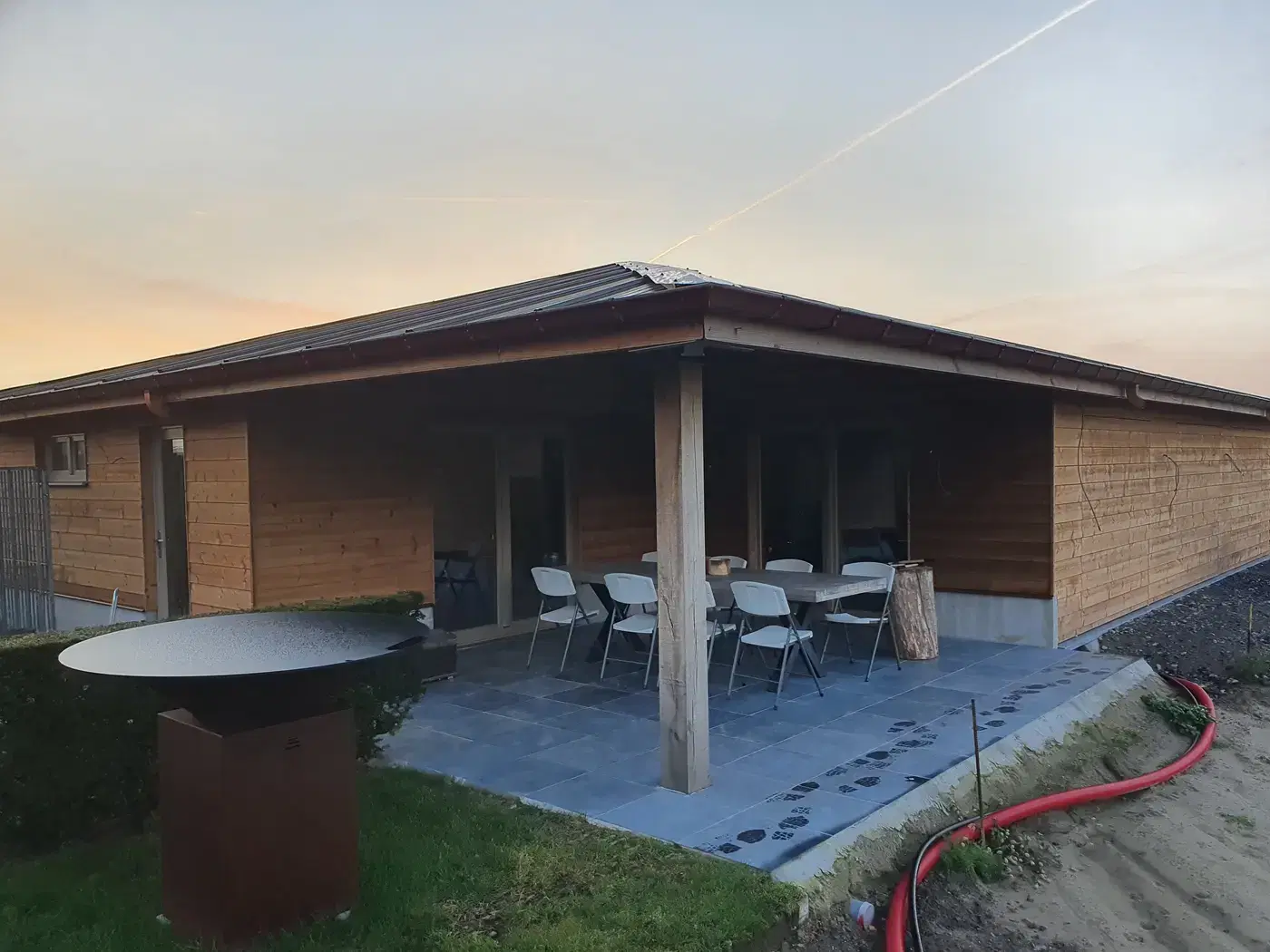 Afgewerkt houten bijgebouw met overdekt terras in warm avondlicht