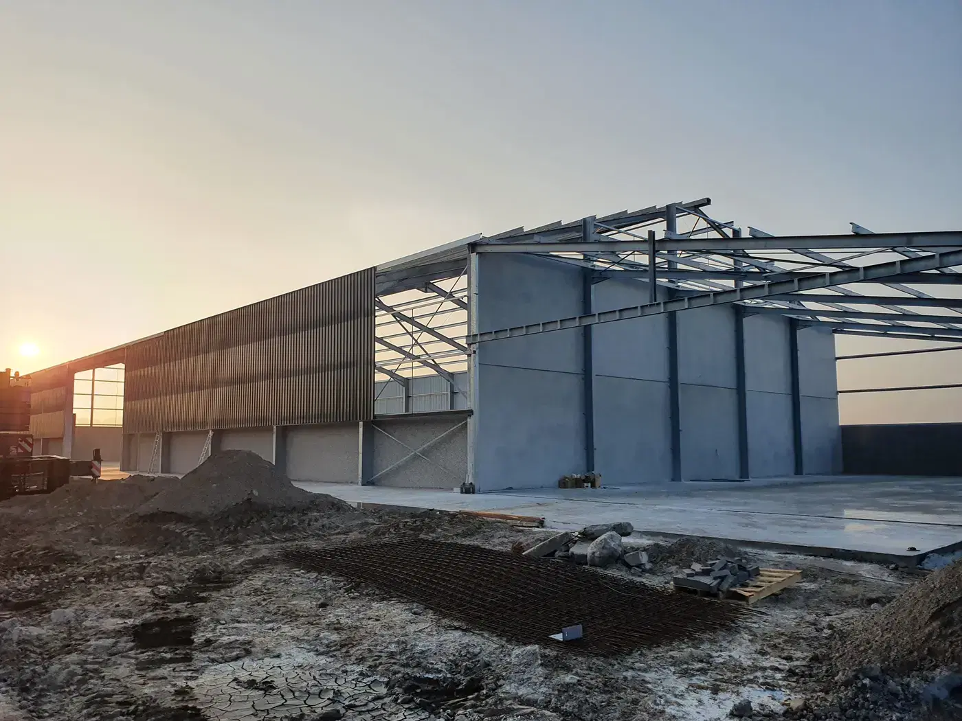 Staalskelet van een hangaar in opbouw bij zonsopgang