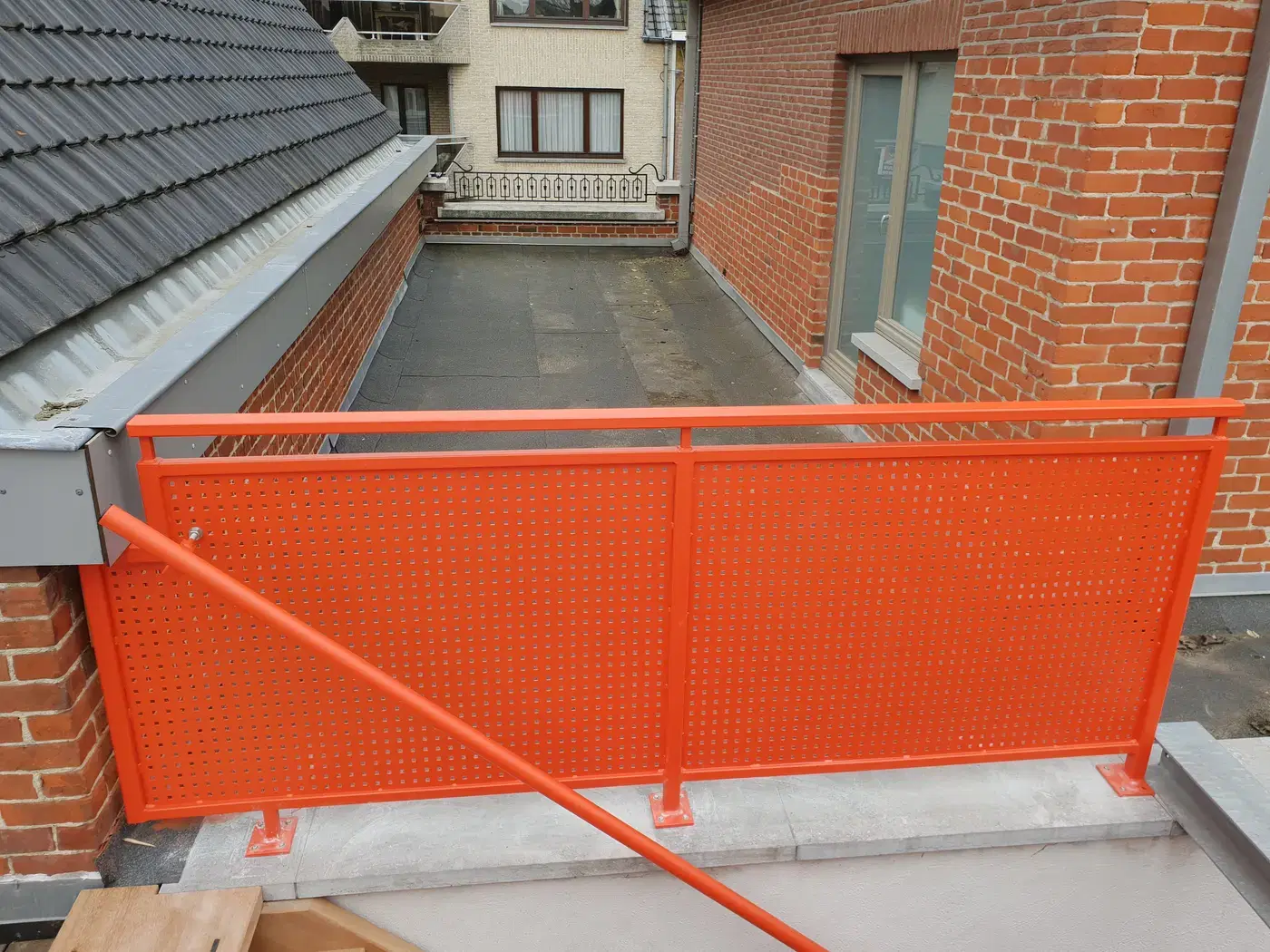 Oranje gemoffelde balustrade in geperforeerde plaat op een dakterras
