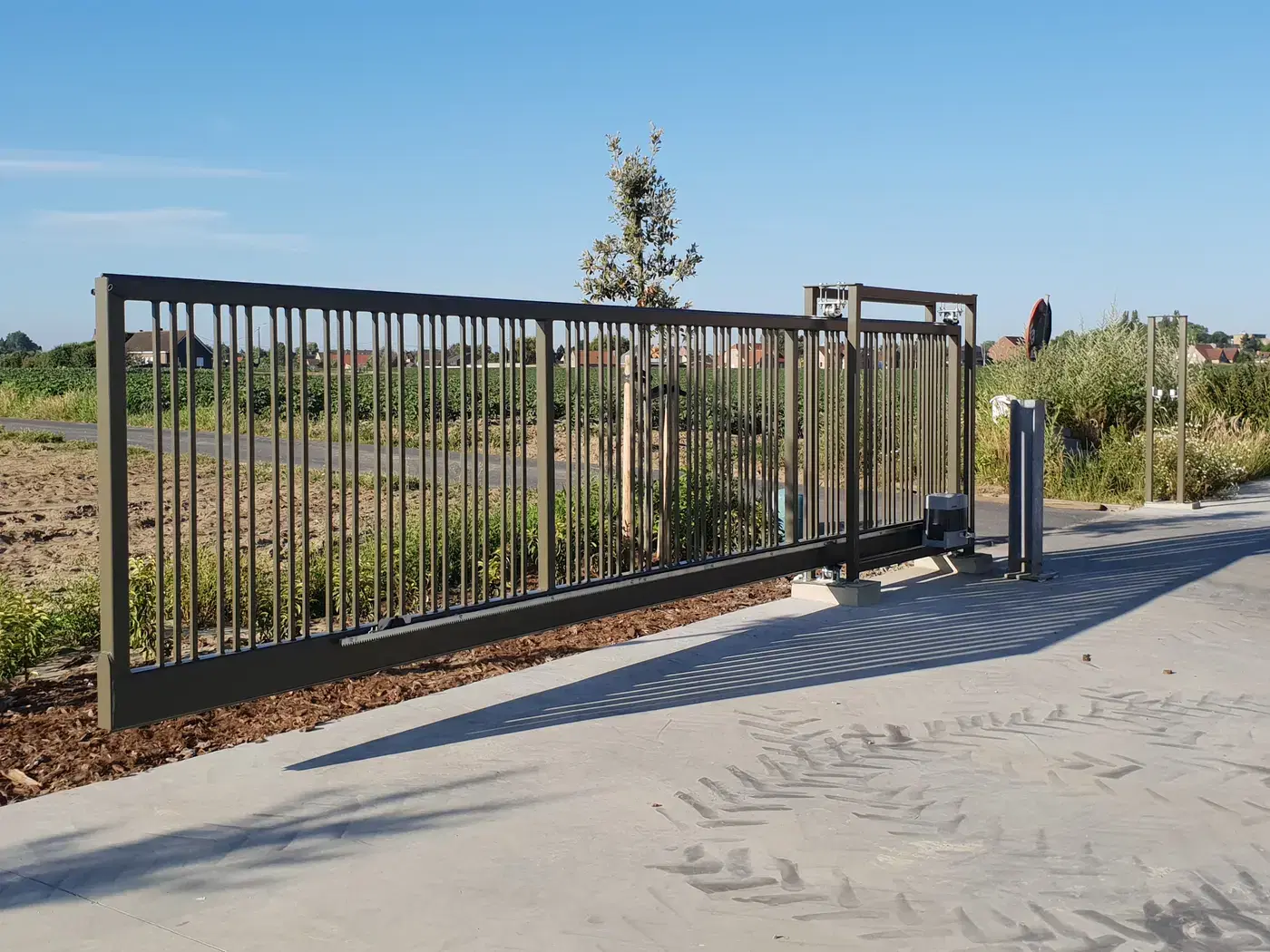 Automatische stalen schuifpoort met verticale spijlen in avondzon