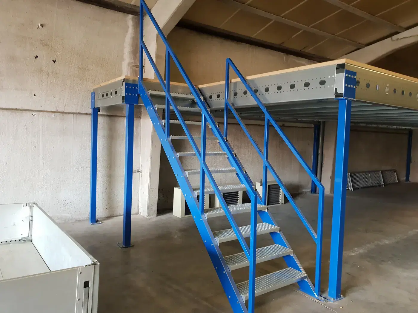 Blauwe stalen trap met roostertreden naar een nieuwe mezzanine