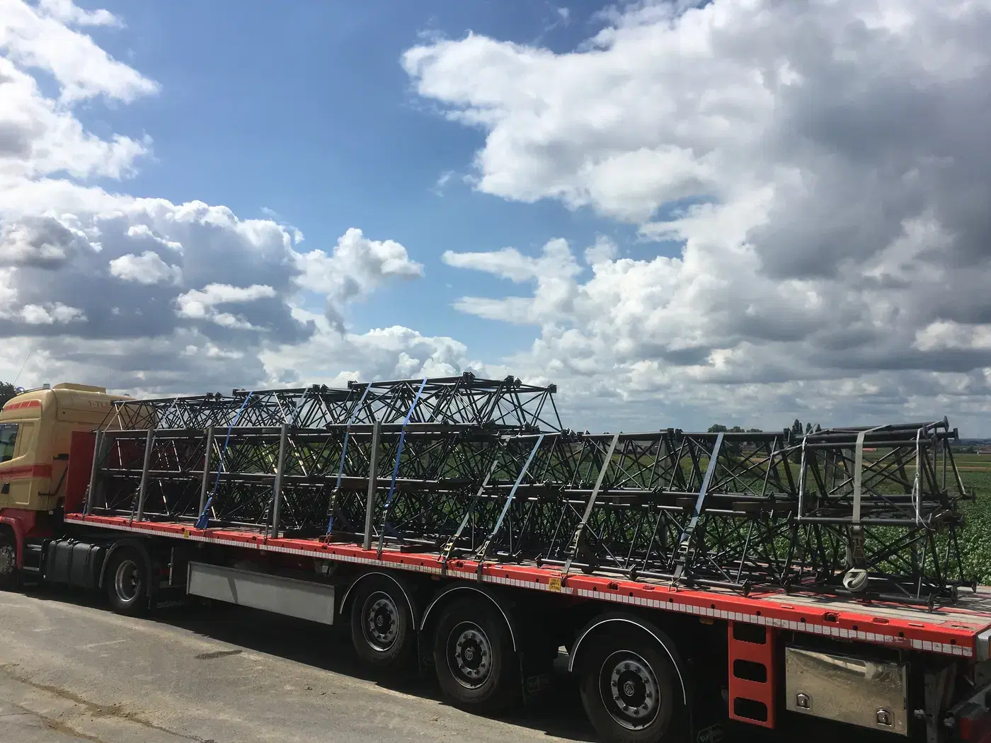 Vrachtwagen geladen met zwarte gelaste vakwerkliggers