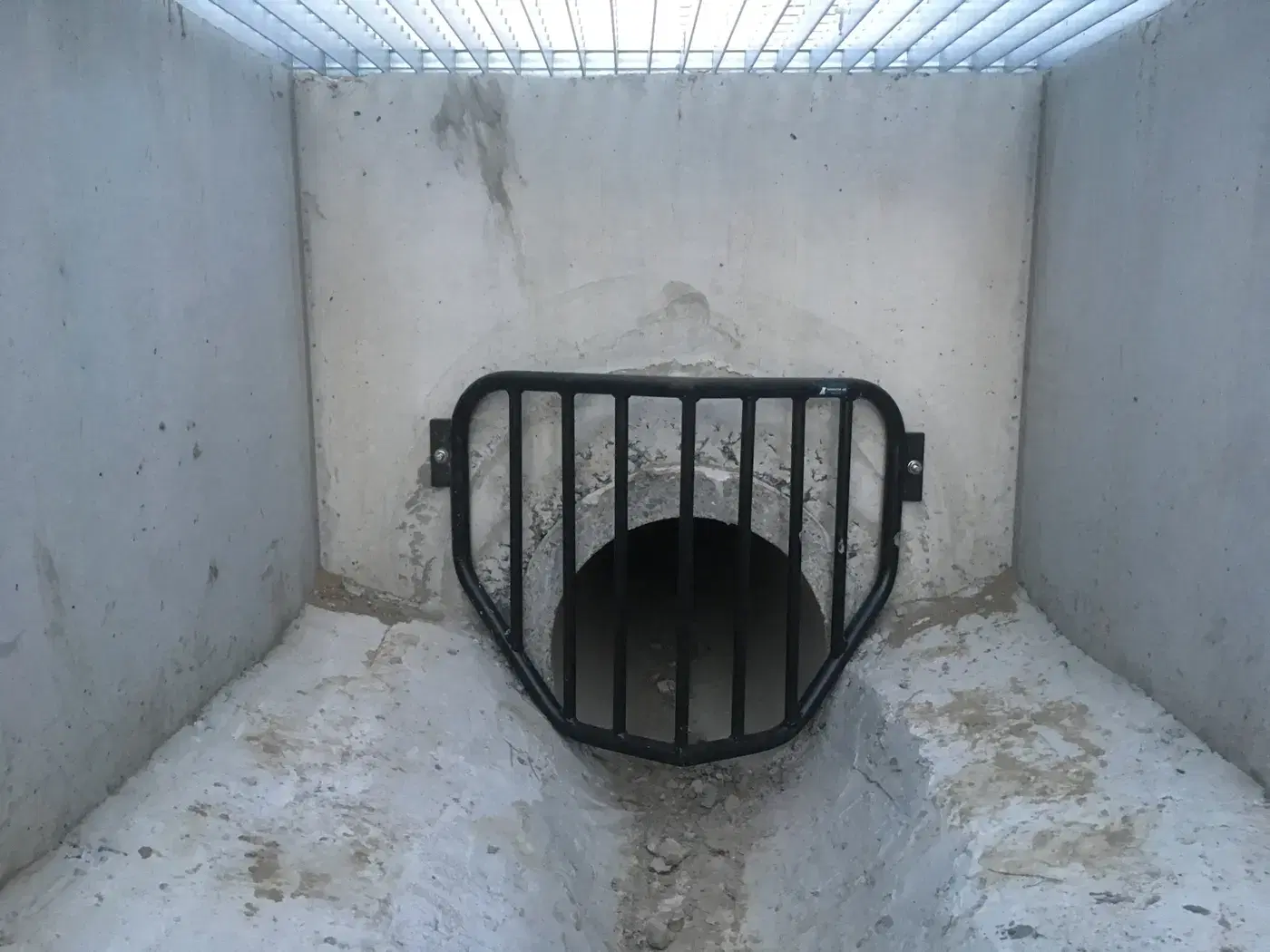Zwart gelast veiligheidsrooster voor een betonnen duikeropening